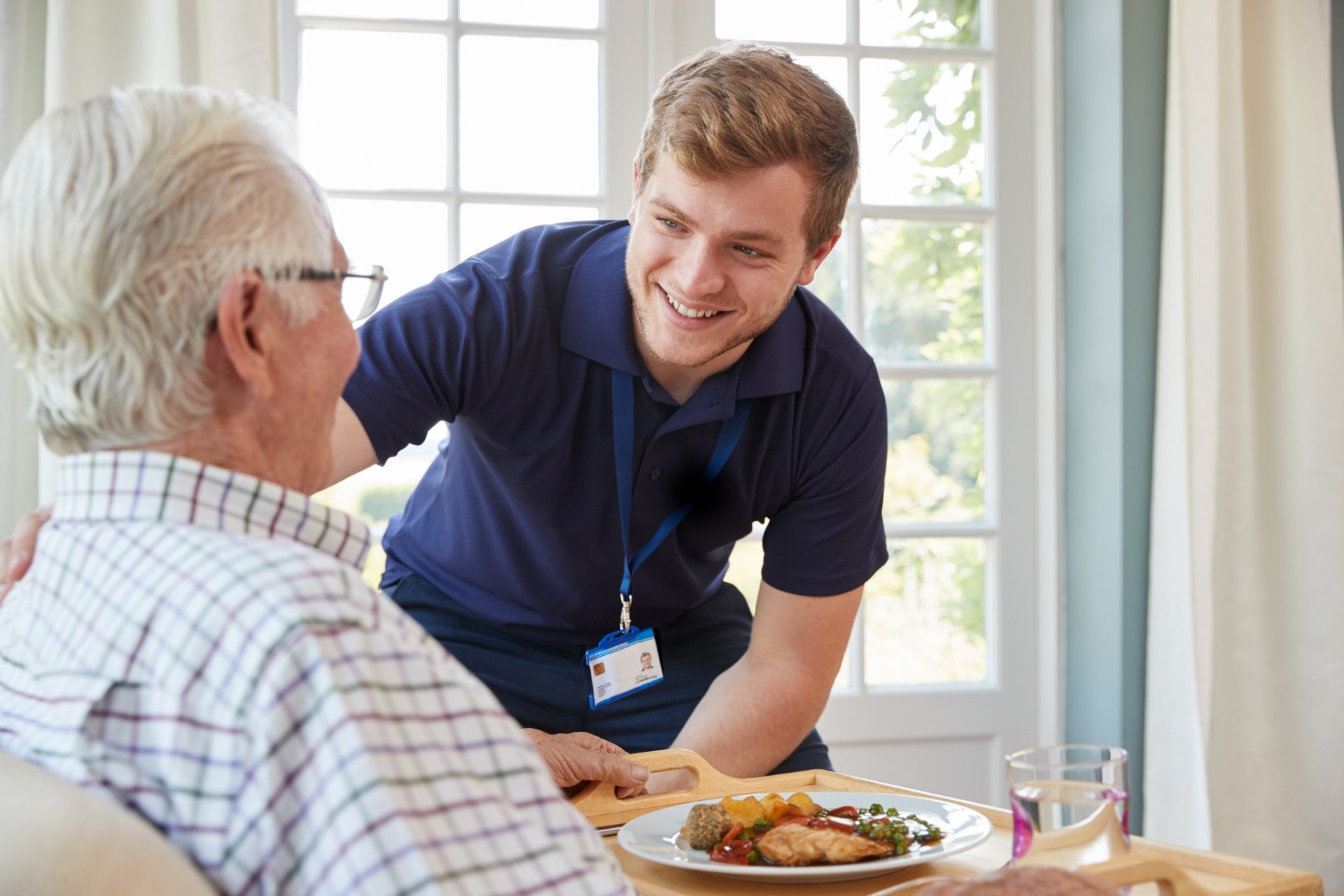Live-in carer sharing a warm meal with an elderly client at home